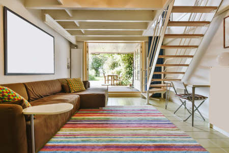 Attractive living room with brown sofa and staircase