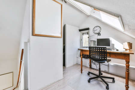 Stunning attic for a work room with a wooden table and a computerの写真素材