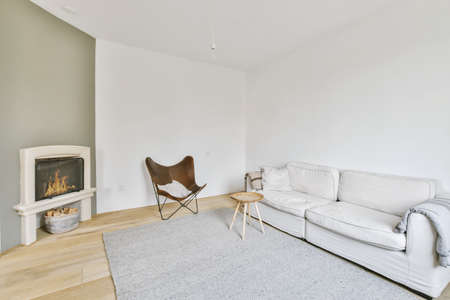 Real photo of a comfy living room interior with fireplace, a round table on gray rug, stylish chair...