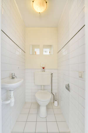 Bright white toilet room with mirrors on the wall,sink and toilet