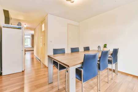 Wooden table and chairs in modern kitchen with large window front in stylish apartment