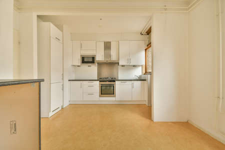Interior of a stylish modern kitchen room with white cabinets and a white fridge