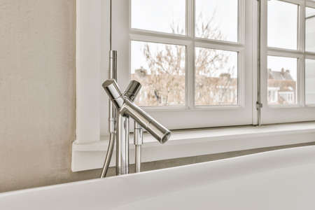 Stunning bathtub design with a convenient faucet next to the windowの写真素材