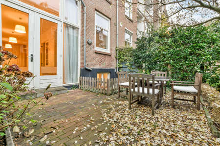 a set of wooden table and chairs in the beautiful green garden of the house