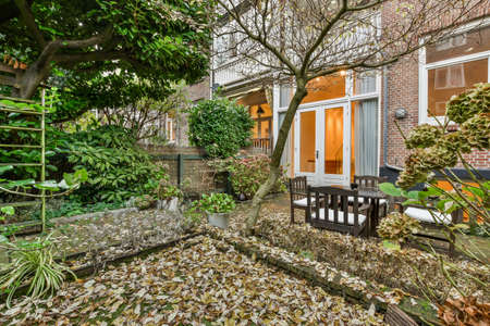 a set of wooden table and chairs in the beautiful green garden of the house