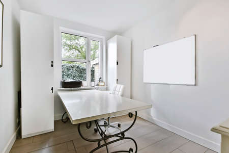 A bright room in a minimalist style with a window and a large white table
