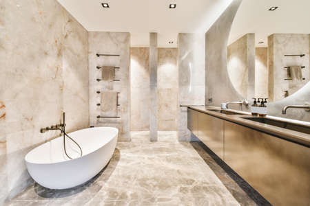 Attractive bathroom with oval bathtub and marble floor and walls
