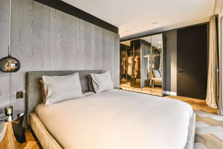 An attractive bedroom in a minimalist style with a soft double bed covered with a beige bedspread