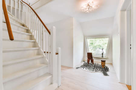 The interior of a beautiful white staircase with comfortable handrails and parquet floorの写真素材