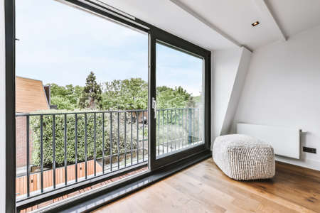 Stylish room with a huge window and an ottoman next to the radiatorの写真素材