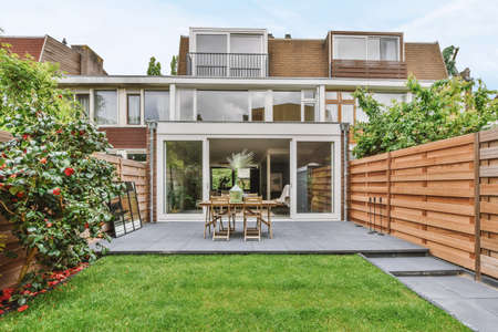 Stylish and well-maintained courtyard of the house with wooden table and chairs and a fresh lawn
