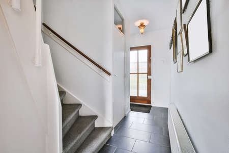 A beautiful narrow corridor with lots of paintings on the wall and a staircase