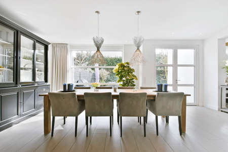 A minimalist dining room with two chandeliers hanging over a wooden table