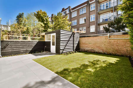 Stylish courtyard of the house with a fresh lawn in daylight