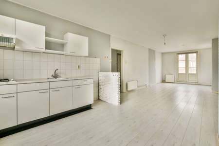 Corner kitchen of a light shade in a minimalist style in a studio apartment