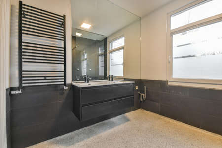 Double sink under a large mirror in a modern bathroom tiled in a minimalist styleの写真素材