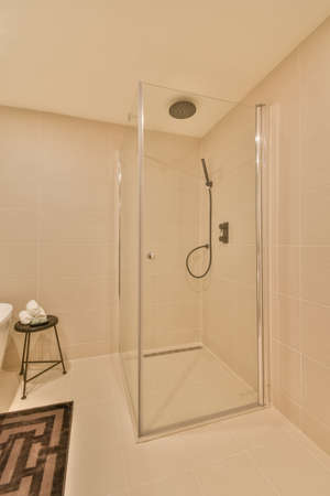 The interior of the bathroom with a glassed shower cabin on a background of flesh-colored tiles