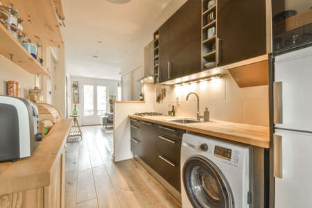 A small kitchen with dark furniture and a wooden countertop in a modern cozy apartment