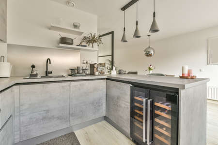 The interior of the kitchen in a gray design with modern equipment in a cozy house