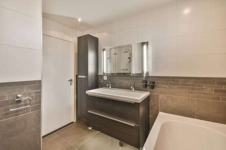 The interior of a bathroom in a modern house decorated with tiles with a bathtub and ceramic sink