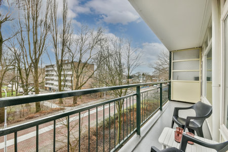A small balcony overlooking the city street with a place to relax in the form of two chairs and a...