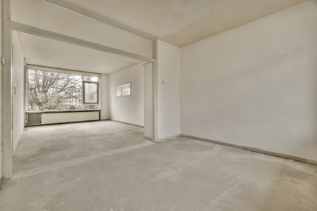 A small, empty room in white tones with a concrete floor in a cozy apartmentの写真素材