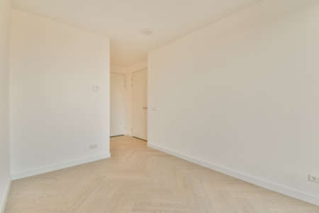 A small, empty room in white tones with a parquet floor in a modern apartment
