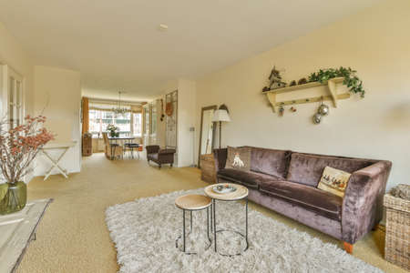 The interior of a spacious living room with a dining area, a panoramic window and lots of house...