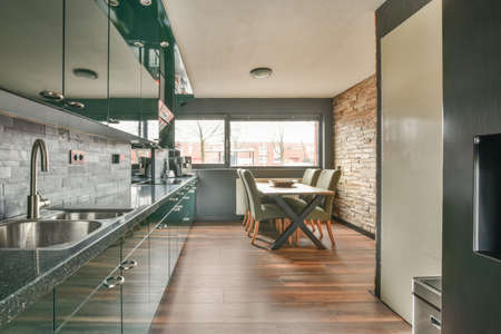 Dining area and kitchen in a green design with wooden floors in a cozy modern houseの写真素材