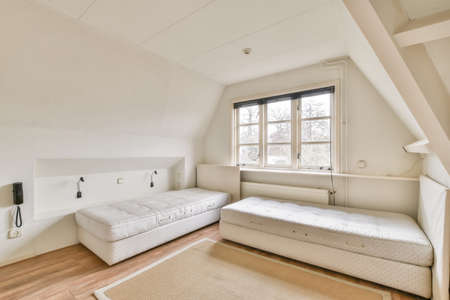 A bedroom with a two small beds and carpet on the floor by the window in a cozy private house