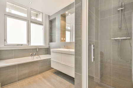 Bathroom in grey design with ceramic bathtub and sink and shower