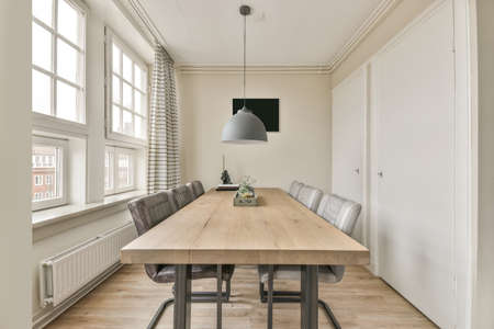 A dining area with a wooden table next to a bright window in a cozy houseの写真素材