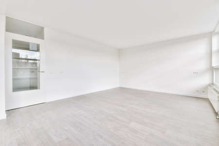 Exit from a small cozy empty room with a parquet floor and a white doorの写真素材