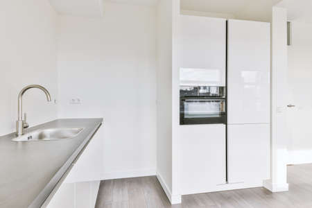 Corner kitchen of a light shade in a minimalist style in a studio apartment