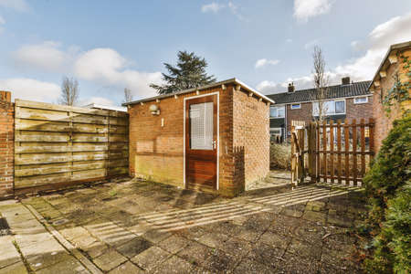 A spacious backyard with tiled floors and a small warehouse near a cozy apartment buildingの写真素材