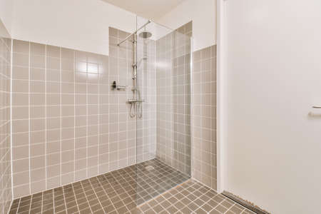 Glass shower with brown tiles decoration and white doorの写真素材