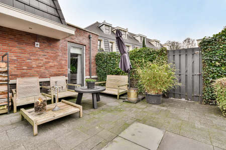 A spacious courtyard behind a residential building with a separate seating area on a tiled floor