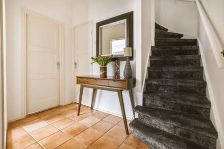 A spacious corridor with tiled floors and a carpeted staircase leading up to a cozy house