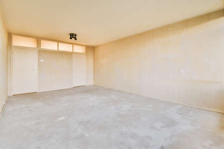A spacious empty room with bare walls and floor in a cozy house