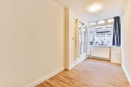 Spacious empty room with a large window and a laminate floor in a cozy house