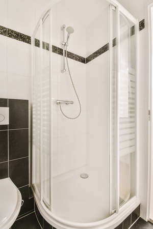 Bathroom interior finished with ceramic black and white tiles with a shower cabin in a modern houseの写真素材