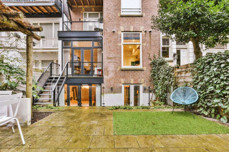General view of the backyard with tiled floor and a dining area under a canopy, behind the apartment...