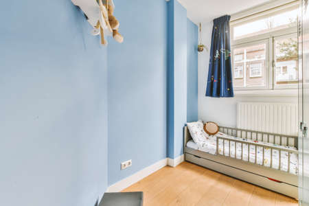 A spacious childrens room with a bed with fences in bright colors in a cozy modern houseの写真素材