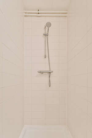 View of the bathroom with shower surrounded by white tiles in a modern house