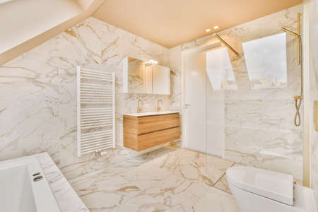Marble bathroom with glazed shower, bathtub, toilet and ceramic sink in a modern house