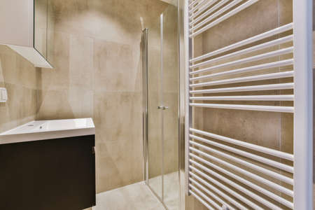 Glass partition between shower cabin and sink under the mirror in modern restroom at home