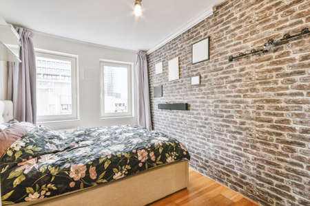 A spacious bedroom with a flower bed by bright windows on a wooden floor