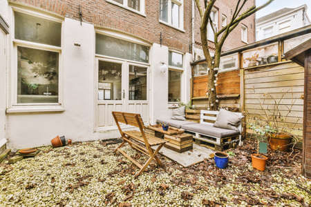 Backyard with seating area, barn, gravel on the ground and trees and entrance to apartment