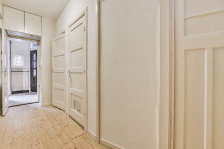 A spacious straight corridor with several doors on the sides leading inside to a cozy house