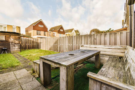 Neat paved patio with sitting area and small garden near wooden fence